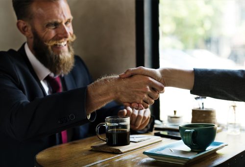 Two people shaking hands over coffee