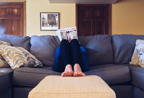 Person readying magazine on sofa