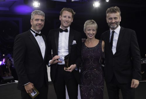 Group posing with an award at a black-tie gala