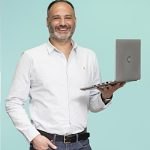 Man in a white shirt holding a laptop