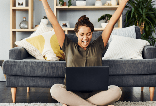 Woman celebrating with arms raised on a sofa