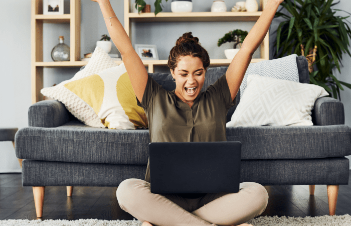 Woman celebrating with arms raised on a sofa