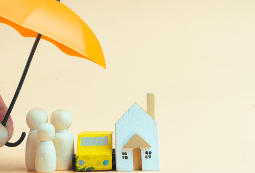 Umbrella sheltering wooden family figures and a model house