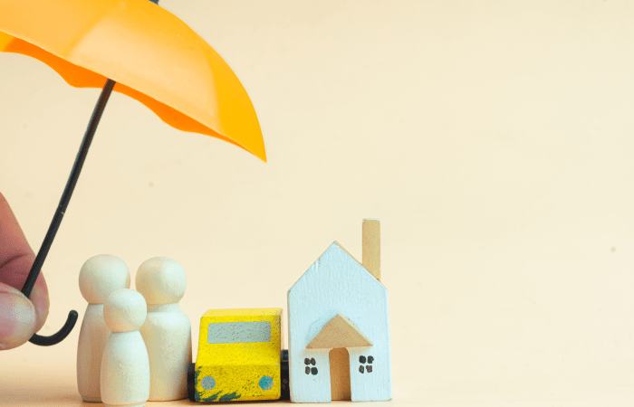 Umbrella sheltering wooden family figures and a model house