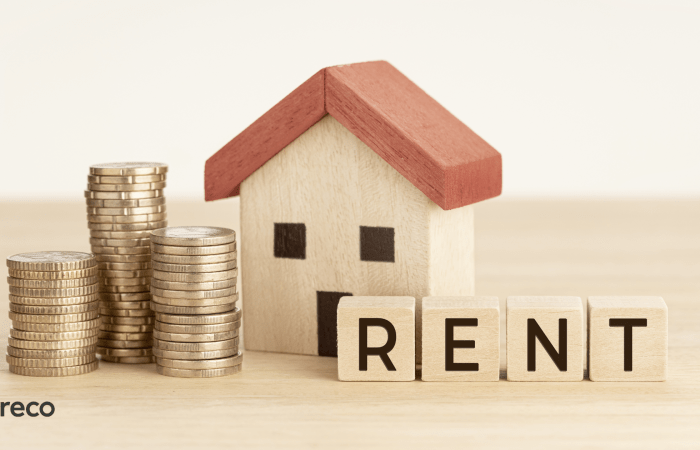 Stacked coins beside a model house with a Rent sign
