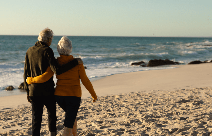 Couple walking arm in arm along a beach