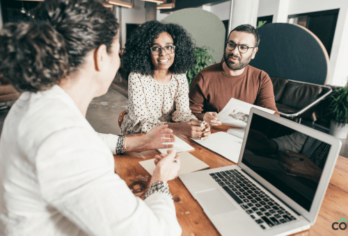 Colleagues gathered around a laptop in a meeting