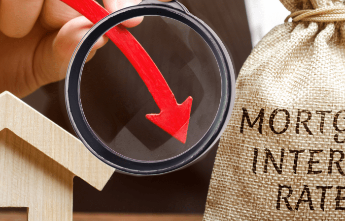 Magnifying glass over mortgage interest rates text with a red downward arrow